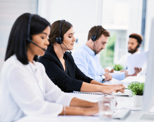 Eine Reihe von Büro-Mitarbeitenden mit Headset vor ihren Bildschirmen sitzend